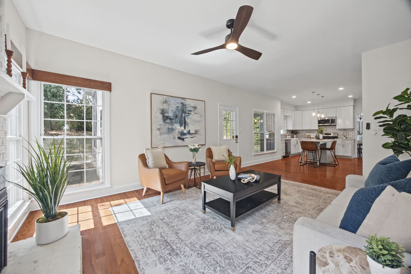 The family room and kitchen as one open space, with sunlight across the hardwood floor.